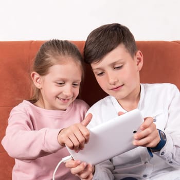 Boy/brother who shows a girl/sister how to play on her digital tablet