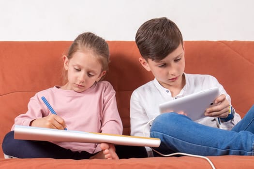 Two children playing, one with the coloring book and the other with the digital tablet