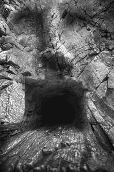 cave in the mountains, a human face. fantastic picture