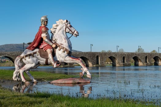 PONTE DE LIMA, PORTUGAL - CIRCA APRIL 2018: Statue of Roman soldier in front of the Roman bridge crossing the Rio Lima in Portugal.