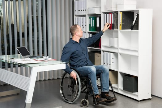 disabled businessman in wheelchair taking a folder in the office