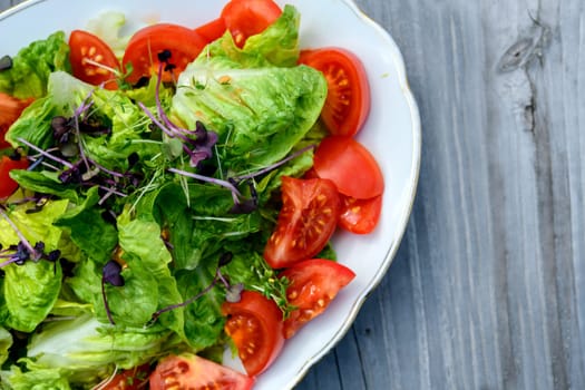 mixed summer salad on plate and wooden ground