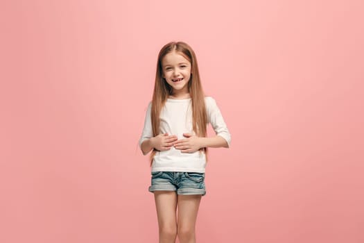 Happy teen girl standing, smiling isolated on trendy pink studio background. Beautiful female half-length portrait. Young satisfy girl. Human emotions, facial expression concept. Front view.