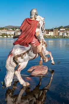 PONTE DE LIMA, PORTUGAL - CIRCA APRIL 2018: Statue of Roman soldier in front of the Roman bridge crossing the Rio Lima in Portugal.
