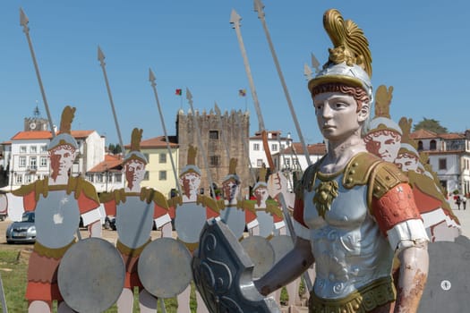 PONTE DE LIMA, PORTUGAL - CIRCA APRIL 2018: Statues of roman soldiers near Lima River at Ponte de Lima with Medieval Tower of the Old Jail on the background.