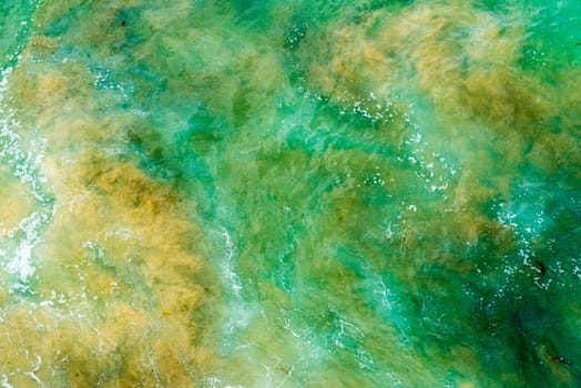 Top aerial view of blue green waves crashing on rocky Australian coastline. Summer seascape with ocean waves. Travel concept background