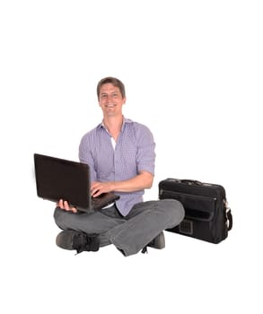 A young smiling man sitting on the floor with his laptop and briefcase.looking up and smiling, isolated for white background.