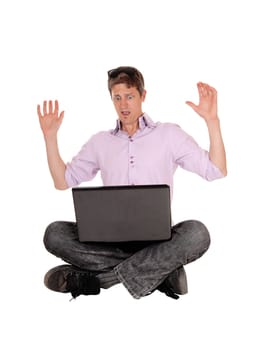 A young man sitting on the floor with his laptop on his knees lifting.his hands what he sees on the screen, isolated for white background.