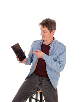 Fanny young man holding his new tablet and enjoying what he.sees and pointing with his finger, isolated for white background.