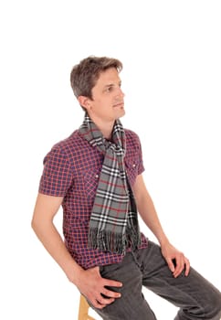 A handsome young man in a checkered shirt and scarf around he.neck sitting relaxed, isolated for white background.
