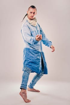 caucasian male dancer wearing blue denim shirt and pants on light background performing hip hop and contemporary style dance.