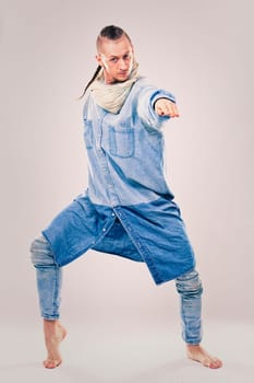 caucasian male dancer wearing blue denim shirt and pants on light background performing hip hop and contemporary style dance.