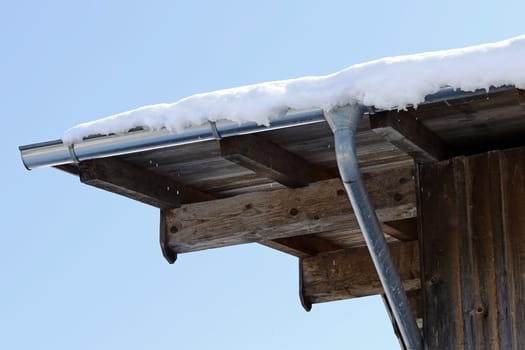 Wooden house with a rain gutter made of sheet metal in winter. Gutter on a wooden house