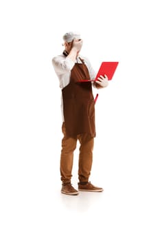 Sorry saddened butcher posing with a laptop isolated on white studio background. The young caucasian male model in full-length. Butcher, professional concept