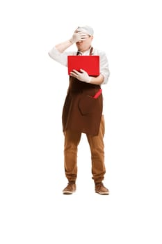 Sorry saddened butcher posing with a laptop isolated on white studio background. The young caucasian male model in full-length. Butcher, professional concept