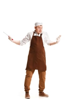 Smiling butcher posing with a knife and mobile phone isolated on white studio background. The young caucasian male model in full-length. Butcher, knife, professional concept