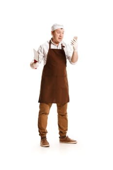 Smiling butcher posing with a knife and mobile phone isolated on white studio background. The young caucasian male model in full-length. Butcher, knife, professional concept