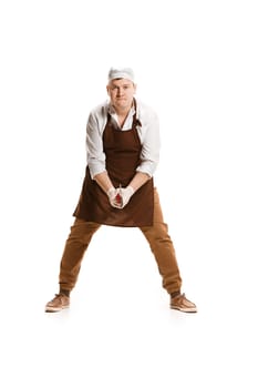 Angry aggressive butcher swinging with a knife isolated on white studio background. The young caucasian male model in full-length. Butcher, knife, professional concept