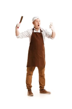 Smiling butcher posing with a knife and mobile phone isolated on white studio background. The young caucasian male model in full-length. Butcher, knife, professional concept
