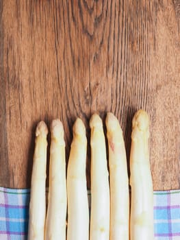 Raw organic white asparagus on a rustic wooden kitchen table, healthy or seasonal food