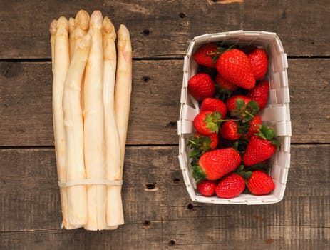 Fresh organic strawberries and white asparagus on a rustic wooden table