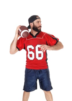 A young football player standing in his uniform and a beard ready to.throw his football, isolated for white background.
