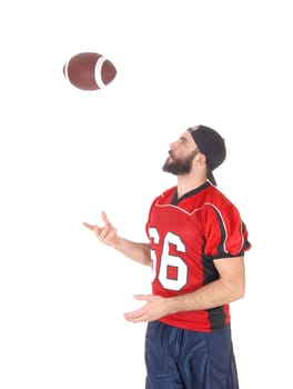 A young football player standing in his uniform and throwing his football.into the air, with a beard, isolated for white background.