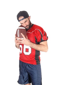 A handsome young football player standing with his ball in his hand.thinking of his next move in the game, isolated for white background.