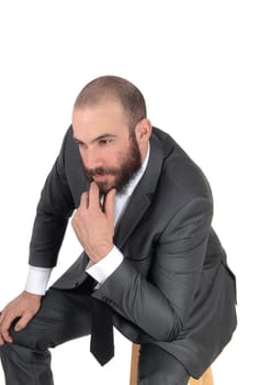 A young businessman sitting with his hand on his chin in a suit and .beard and mustache, isolated for white background.