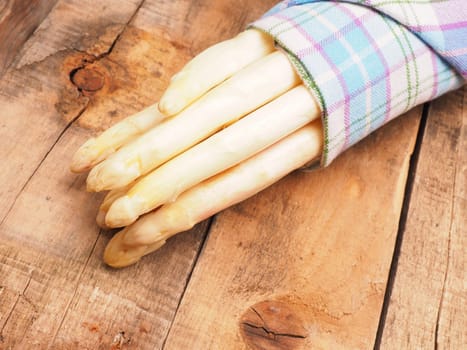 Raw organic white asparagus on a rustic wooden kitchen table, healthy or seasonal food