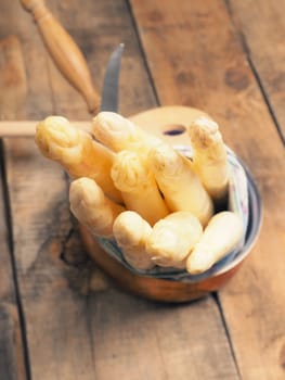 Raw organic white asparagus on a rustic wooden kitchen table, healthy or seasonal food