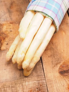 Raw organic white asparagus on a rustic wooden kitchen table, healthy or seasonal food
