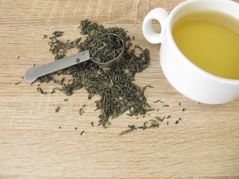 Green tea Chun Mee in tea measure and a cup of green tea