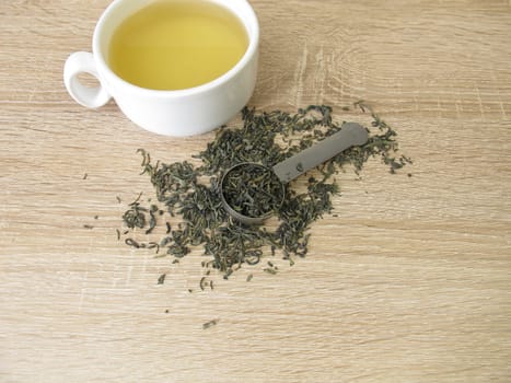 Green tea Chun Mee in tea measure and a cup of green tea