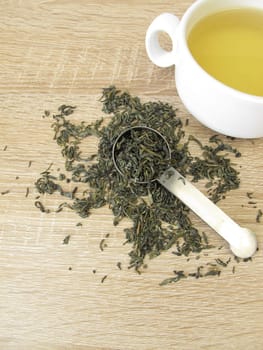 Green tea Chun Mee in tea measure and a cup of green tea