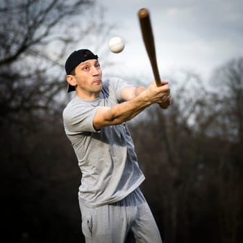 The man is playing baseball outdoors, recreation, sport.