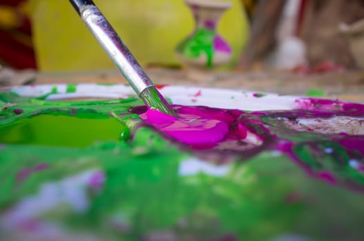 Child loading with purple color her brush. Ceramic workshop for children concept