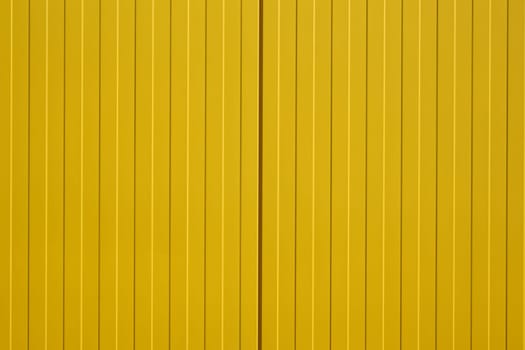 The close-up of a colorful and bright yellow corrugated iron wall of a shopping center.