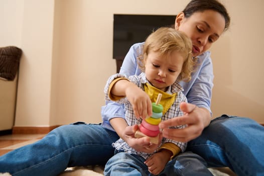 Mother lovingly engages with her toddler while playing with a vibrant educational toy at home, fostering relationship and learning.