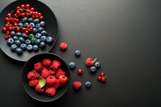 Mix of fresh berries in a bowl on black background