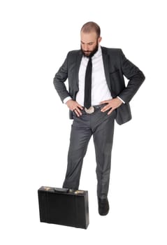 A young handsome business man standing, looking down man thinking.with his briefcase to his feet, isolated for white background.