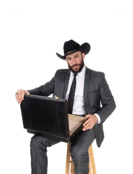 A handsome young business man sitting with his briefcase on his knees.wearing a black cowboy hat, isolated for white background.