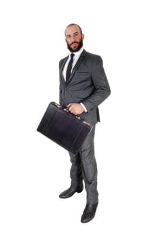 A young handsome business man standing in profile and holding his.black briefcase, isolated over white background.