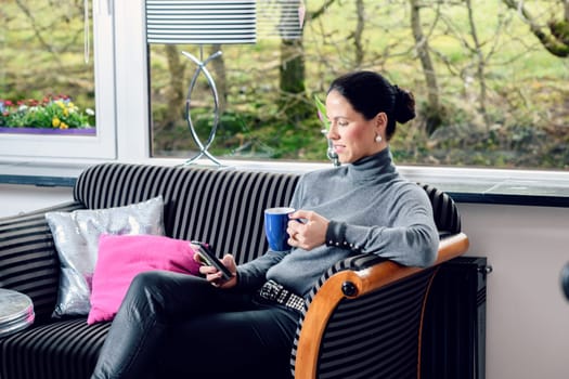 young dark haired woman at home with cup of coffeee relaxing