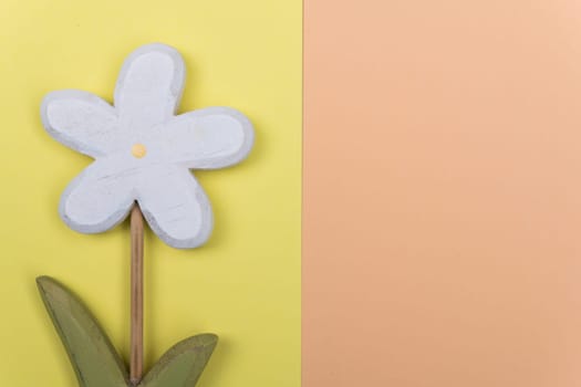 wooden marguerite flower on yellow and orange ground from above