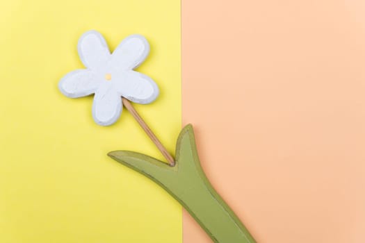 wooden marguerite flower on yellow and orange ground from above
