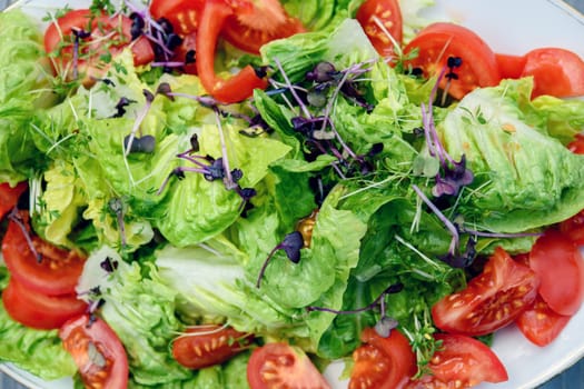 mixed summer salad on plate and wooden ground