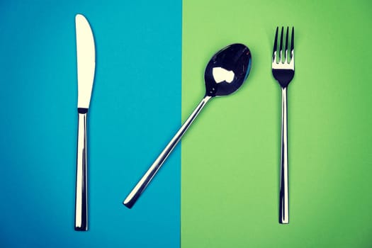spoon, knife and fork on blue and green ground from above