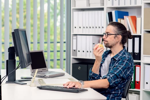 creative man is working in his office and eating apple