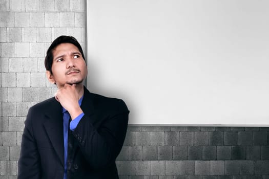 Young asian businessman thinking for solution with whiteboard on the background